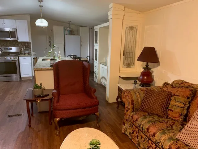 a kitchen with stainless steel appliances a refrigerator a stove a sink and a dining table with wooden floor