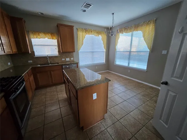 a kitchen with granite countertop a stove a sink a refrigerator and window