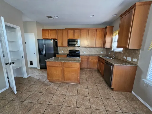 a kitchen with stainless steel appliances granite countertop a stove a sink and a refrigerator