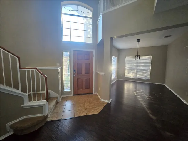 an empty room with wooden floor windows and entryway