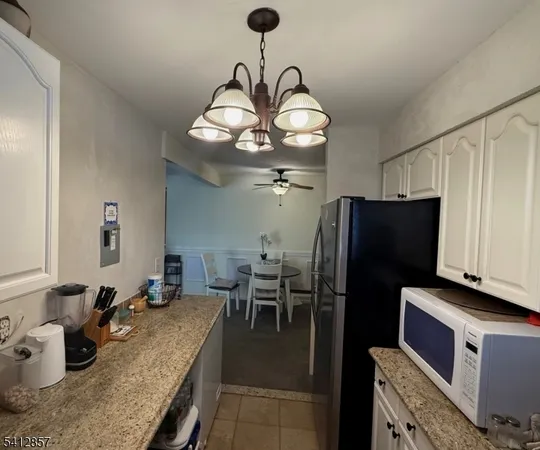 a kitchen with stainless steel appliances granite countertop a refrigerator a sink dishwasher a dining table and chairs with wooden floor