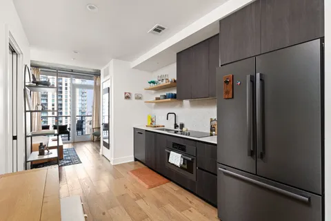 a kitchen with stainless steel appliances granite countertop a refrigerator a sink dishwasher a stove and white countertops with wooden floor