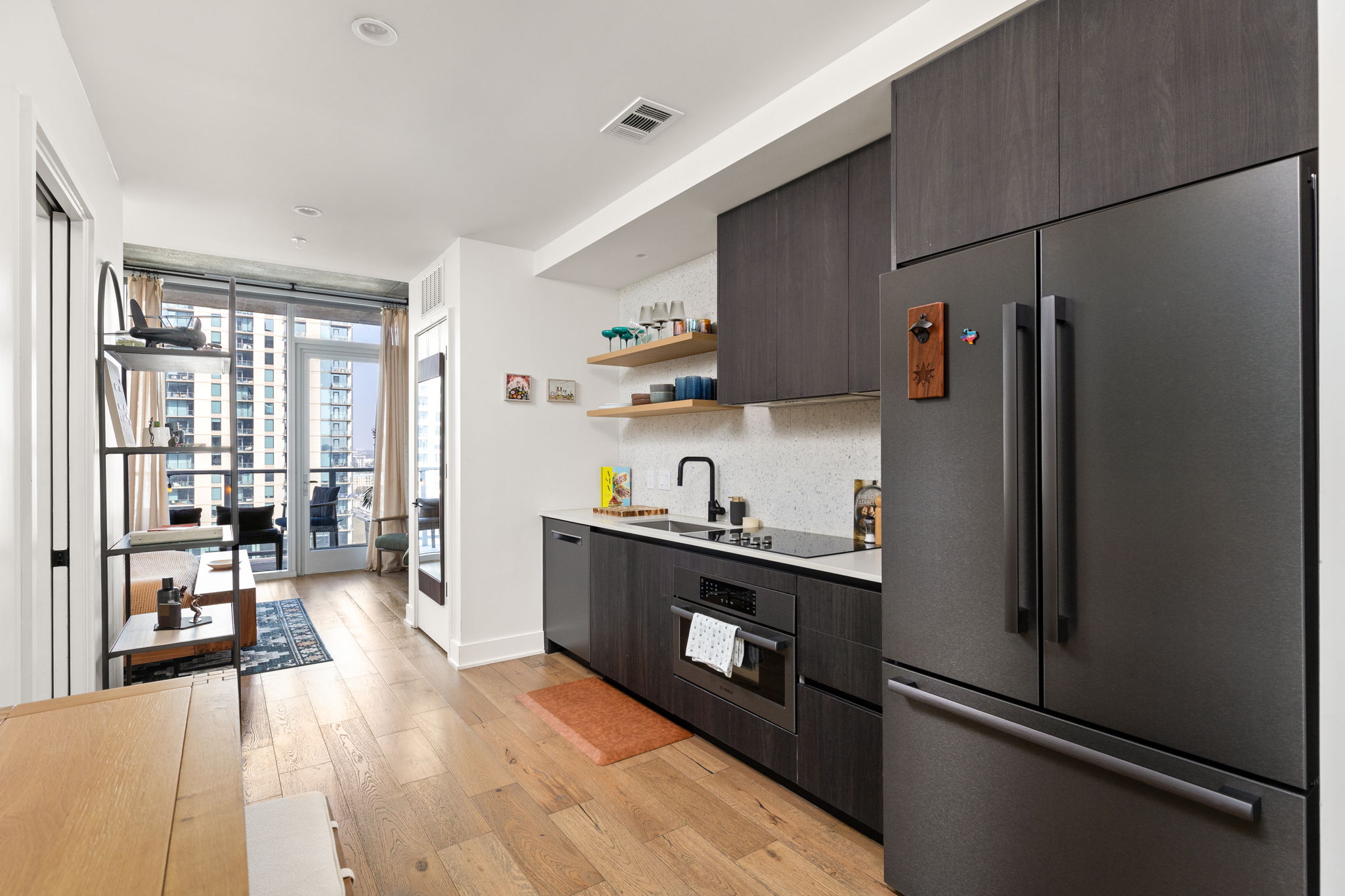 48 East Avenue, Unit 2002 Austin, TX 78701 - Photo 3 of 38 Kitchen featuring stainless steel appliances, open shelves, light countertops, floor to ceiling windows, and light wood-type flooring