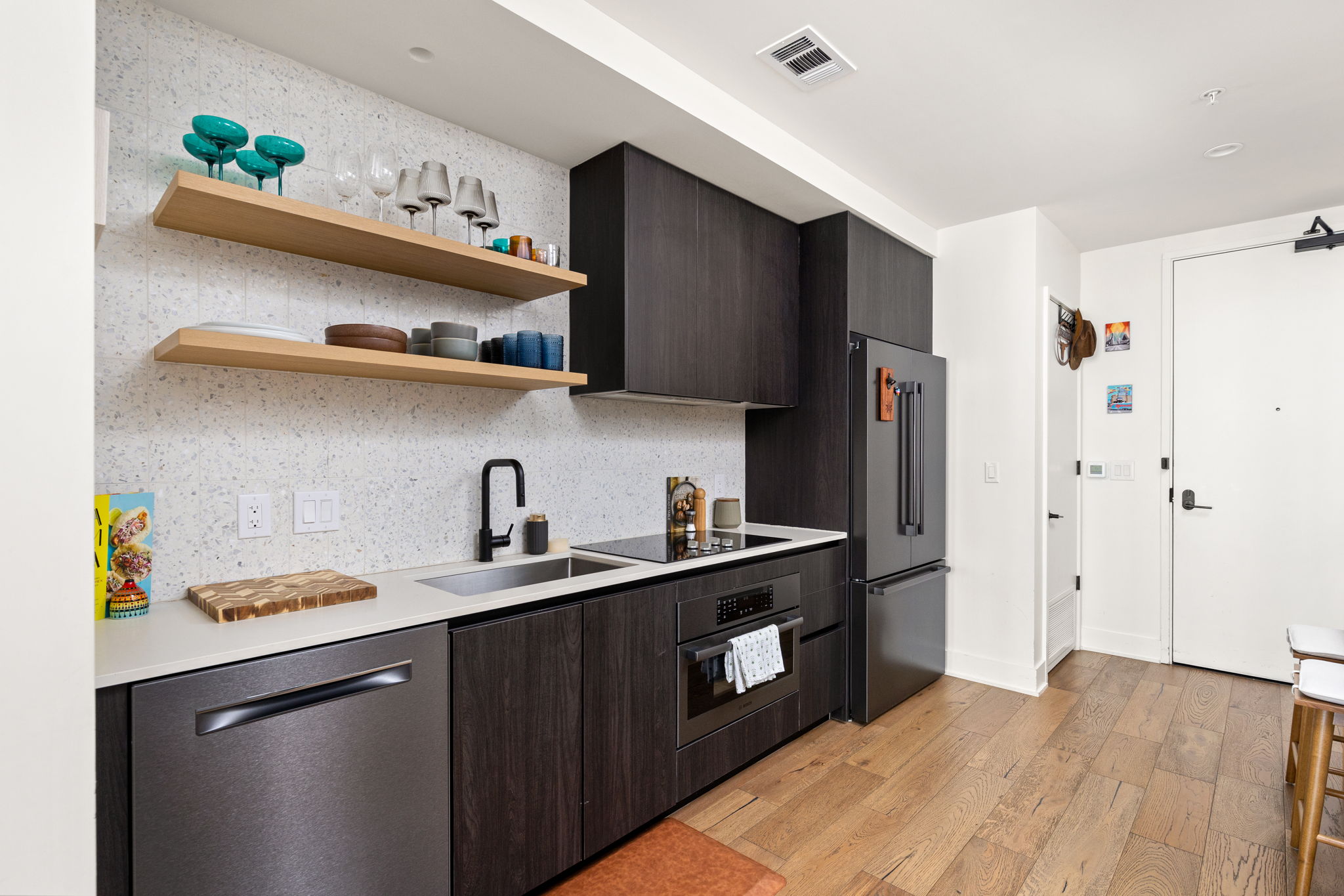 48 East Avenue, Unit 2002 Austin, TX 78701 - Photo 6 of 38 Kitchen featuring stainless steel appliances, modern cabinets, light wood-style floors, open shelves, and tasteful backsplash