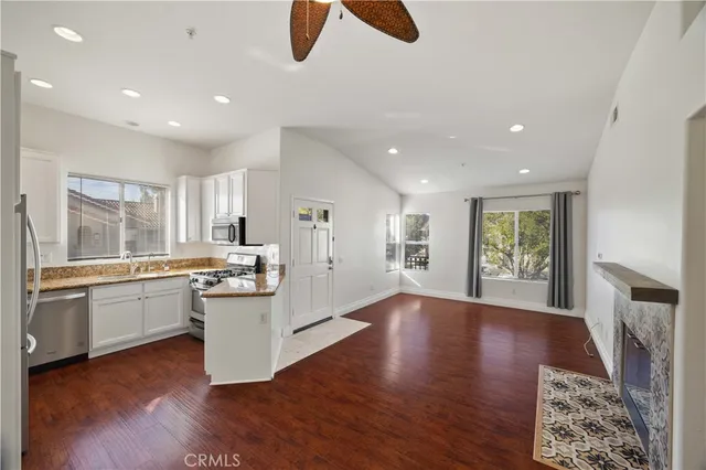 a kitchen with stainless steel appliances granite countertop a stove top oven a sink dishwasher and a fireplace with wooden floor