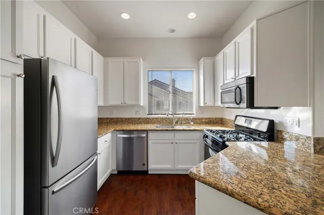 a kitchen with granite countertop a refrigerator stove and sink