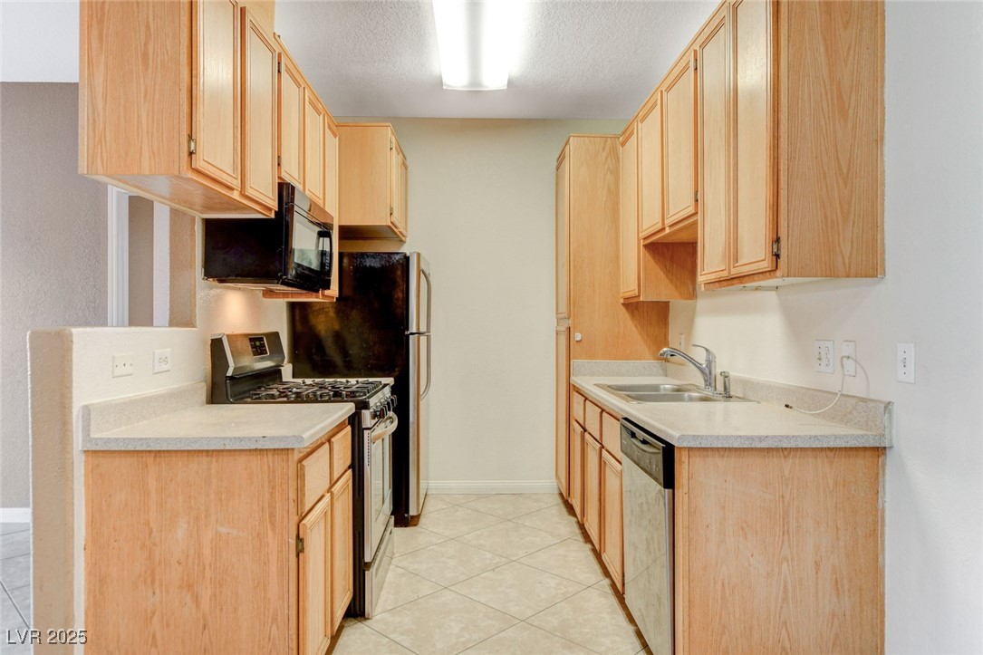 4730 East Craig Road, Unit 1005 Las Vegas, NV 89115 - Photo 14 of 45 Kitchen featuring stainless steel appliances, light brown cabinetry, light countertops, a textured ceiling, and light tile patterned floors