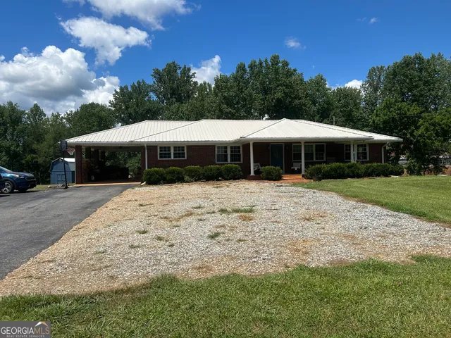 a view of a white house with a big yard and large trees