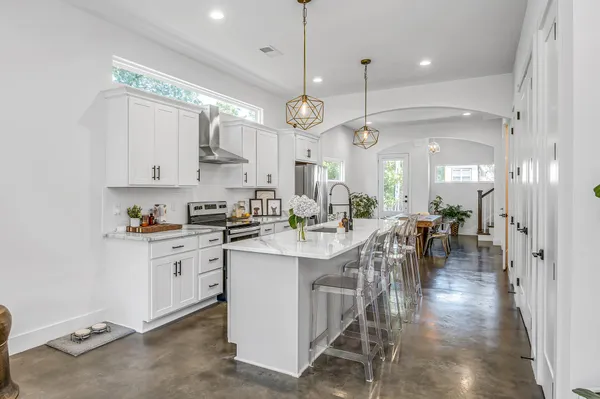 a large white kitchen with lots of counter space and a chandelier
