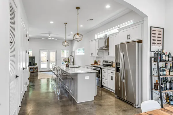 a kitchen with stainless steel appliances kitchen island granite countertop a refrigerator oven a sink a dining table and chairs with wooden floor