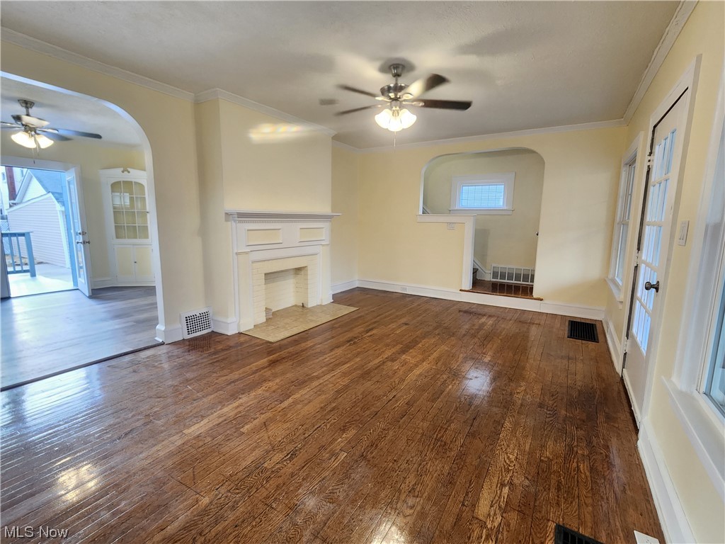 17814 Crestland Road Cleveland, OH 44119 - Photo 4 of 49 Unfurnished living room featuring a fireplace, dark hardwood flooring, crown molding, and ceiling fan