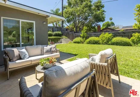a view of a patio with couches chairs potted plants and a large tree