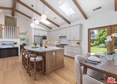 a kitchen with stainless steel appliances granite countertop a stove a sink dishwasher a dining table and chairs with wooden floor