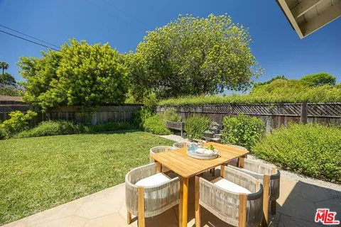 a view of a lake with table and chairs and potted plants