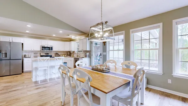 a view of a dining room and livingroom with furniture wooden floor a chandelier