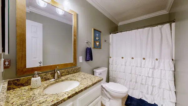 a bathroom with a granite countertop sink a toilet and a mirror
