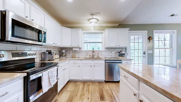 a kitchen with stainless steel appliances granite countertop a stove a sink and a microwave