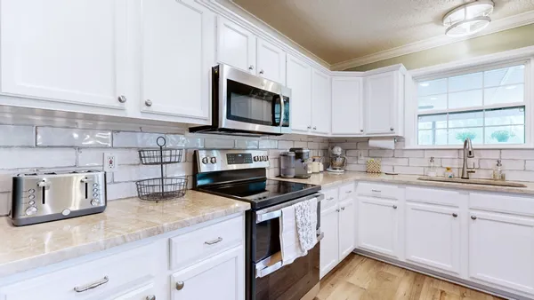 a kitchen with granite countertop white cabinets white stainless steel appliances and sink