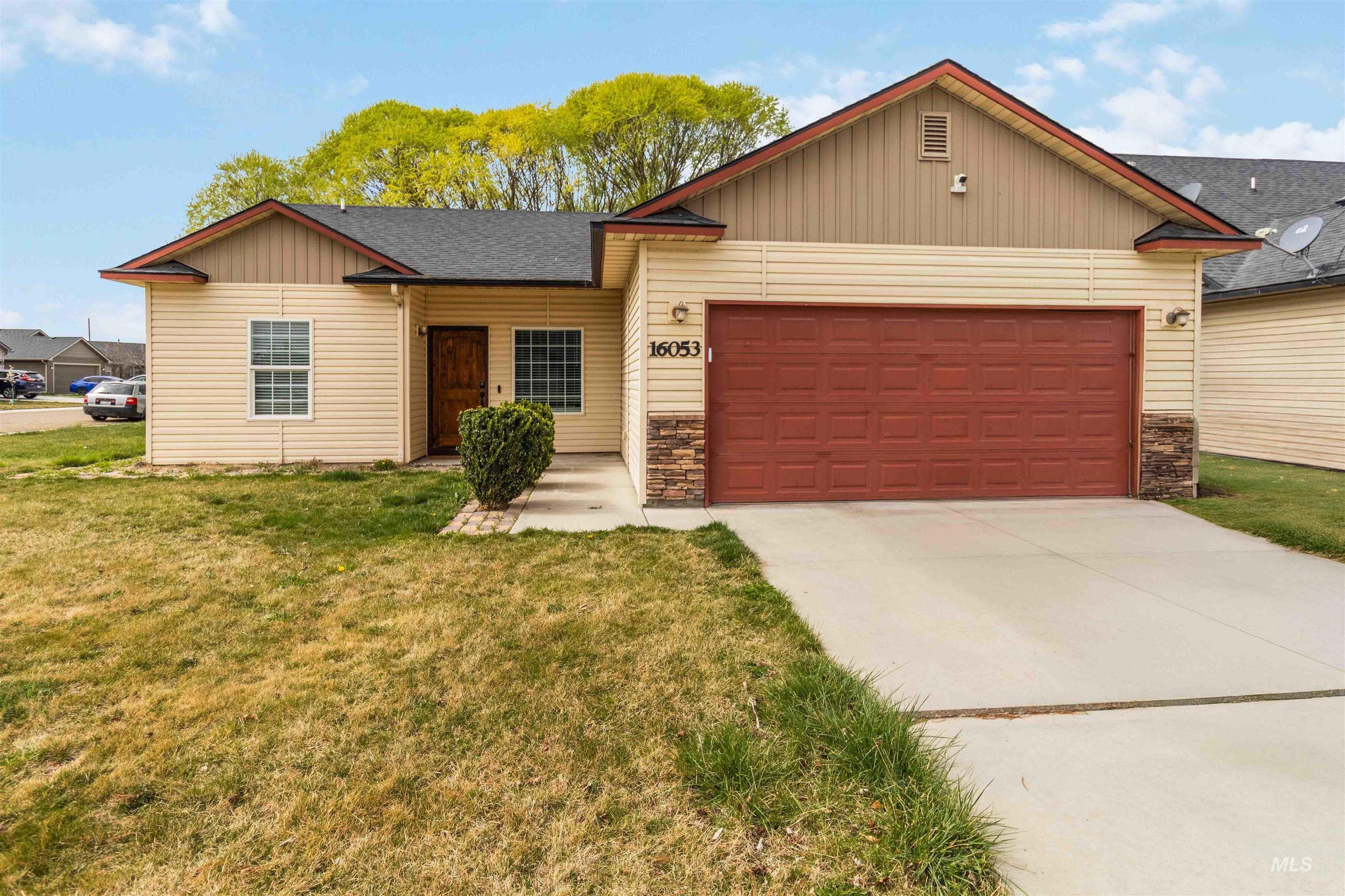 16053 Sunnyfield Avenue Caldwell, ID 83607 - Photo 1 of 35 View of front facade with stone siding, an attached garage, roof with shingles, concrete driveway, and a front lawn