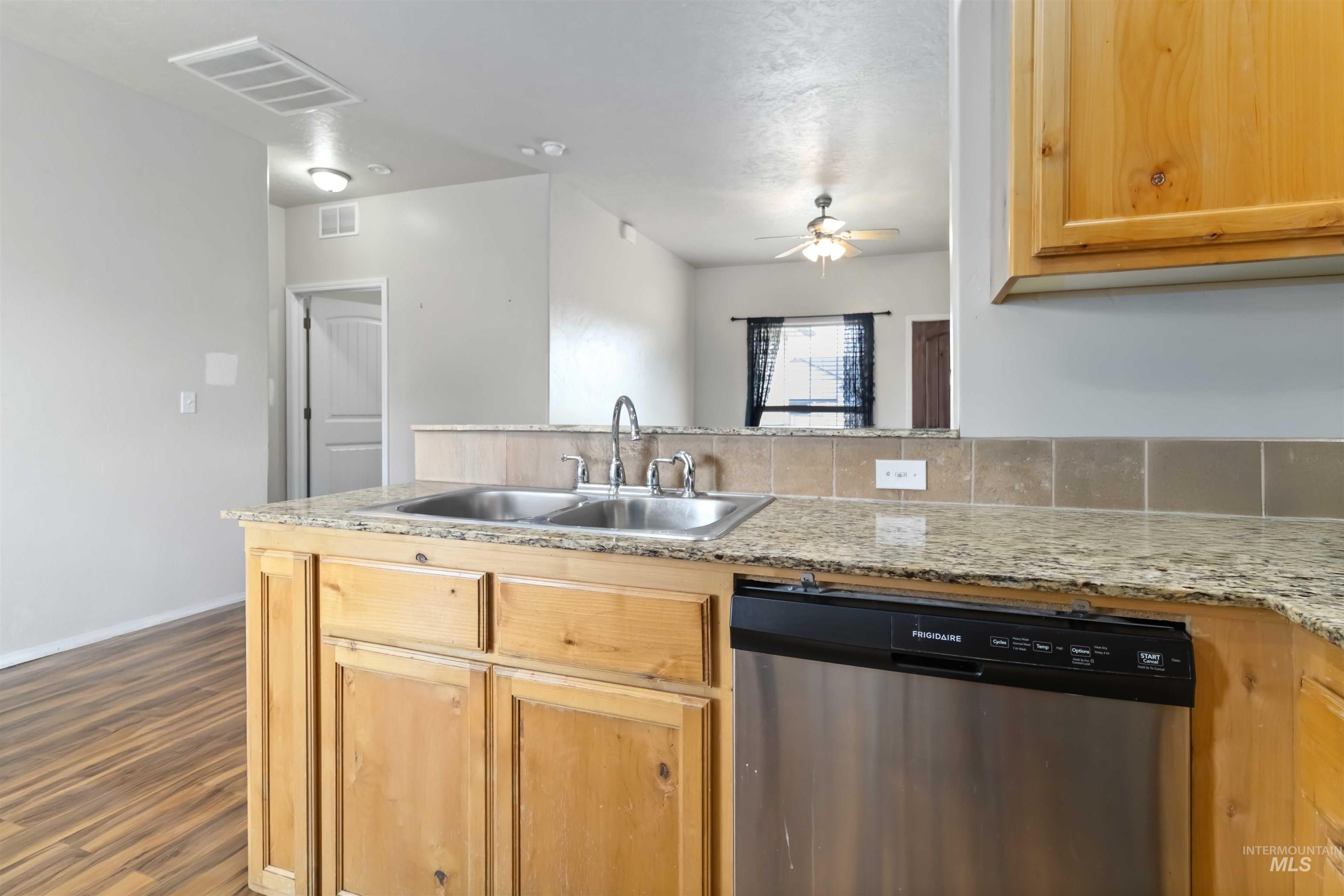 16053 Sunnyfield Avenue Caldwell, ID 83607 - Photo 13 of 35 Kitchen featuring dishwasher, light wood finish cabinetry, ceiling fan, a peninsula, and dark wood-style flooring