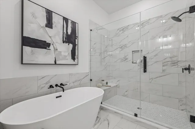 a bathroom with a white bath tub a mirror and a shower