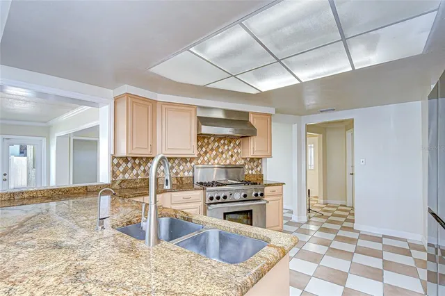 a kitchen with granite countertop a stove a sink and a counter top space