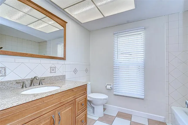 a bathroom with a granite countertop sink toilet and mirror