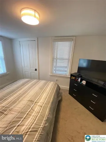 a bedroom with a bed and a flat tv screen on dresser