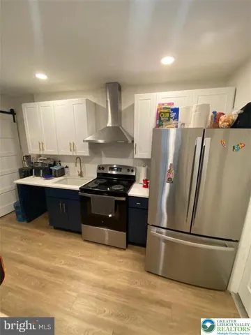 a kitchen with stainless steel appliances a refrigerator a sink a stove and white cabinets