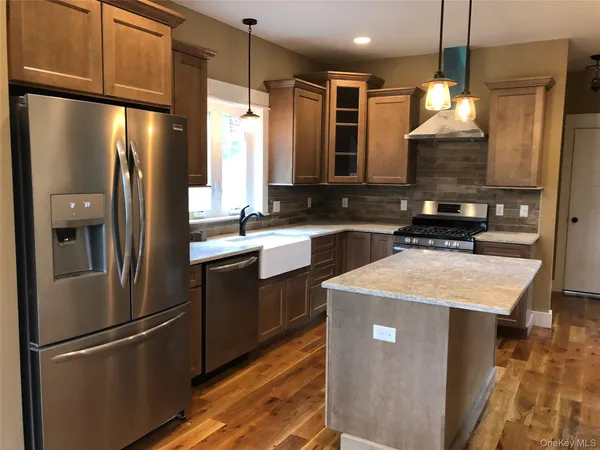a kitchen with stainless steel appliances granite countertop a refrigerator a sink a stove and a wooden floors