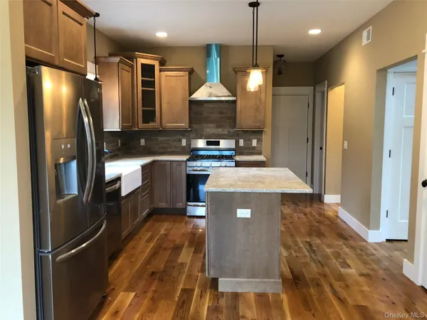 a kitchen with stainless steel appliances granite countertop a refrigerator a sink a stove and a wooden floors