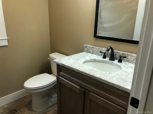 a bathroom with a granite countertop toilet sink and mirror