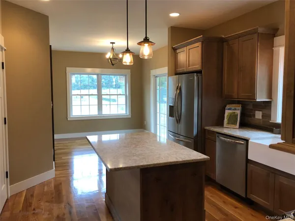 a kitchen with kitchen island granite countertop wooden floor a refrigerator and a sink