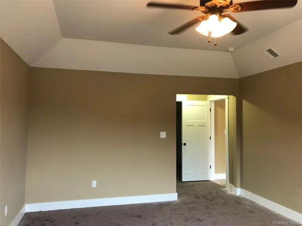 an empty room with a fan and chandelier fan