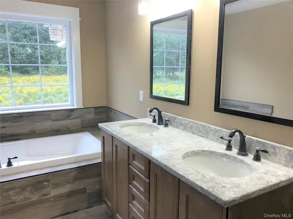 a bathroom with a granite countertop sink and a bathtub