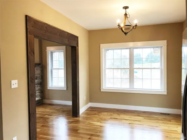 a view of empty room with window and wooden floor