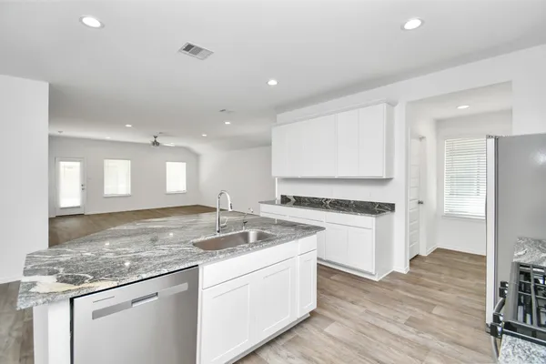 a kitchen with a stove a sink a refrigerator and white cabinets with wooden floor