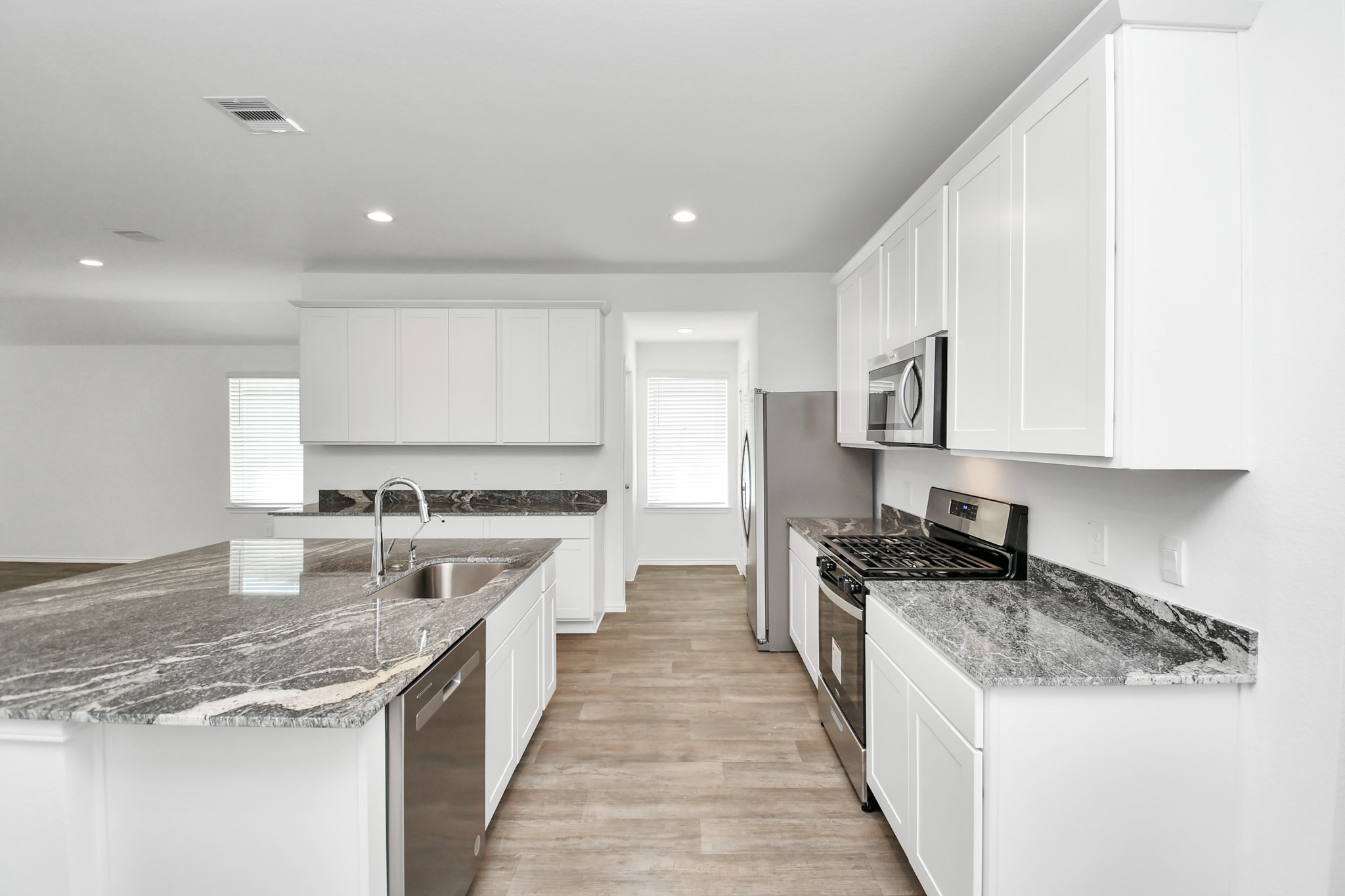 2715 Willow Gulch Way Rosenberg, TX 77469 - Photo 14 of 39 a large kitchen with stainless steel appliances granite countertop a stove top oven a sink a refrigerator and white cabinets