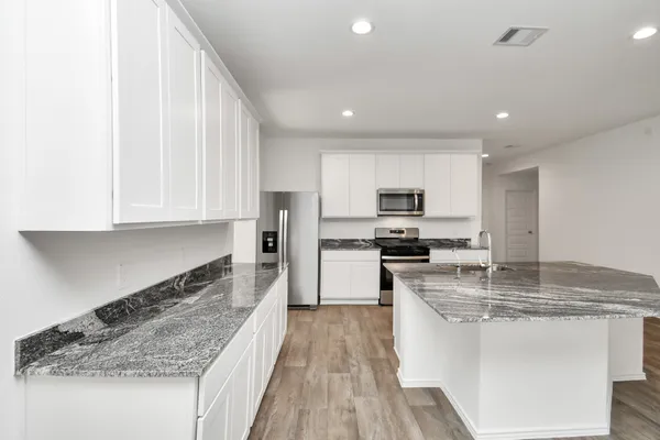 a kitchen with stainless steel appliances granite countertop a stove a sink and a refrigerator