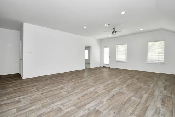 an empty room with wooden floor and windows