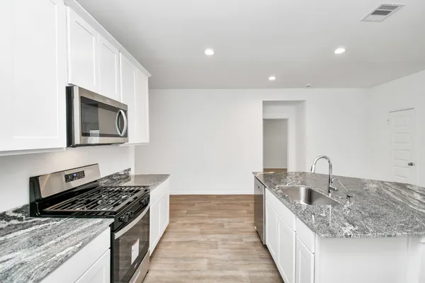 a kitchen with stainless steel appliances granite countertop a sink stove and refrigerator