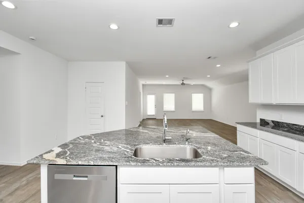 a kitchen with kitchen island granite countertop a sink a stove and cabinets