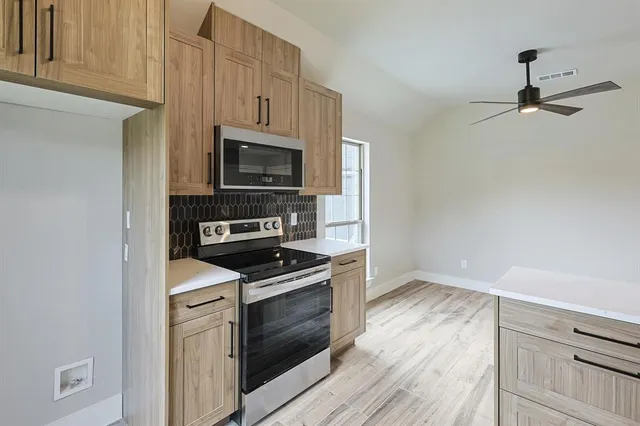 a kitchen with cabinets stainless steel appliances and wooden floor