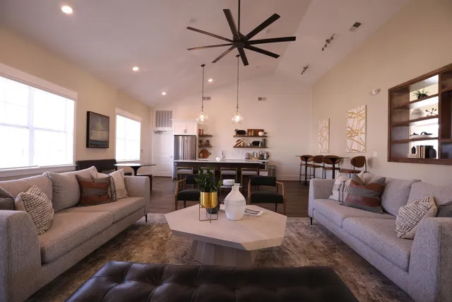 a living room with furniture kitchen view and a large window