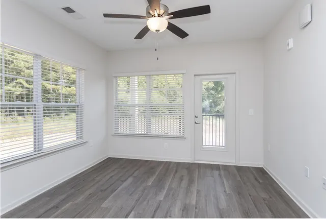 a view of an empty room with wooden floor and a window