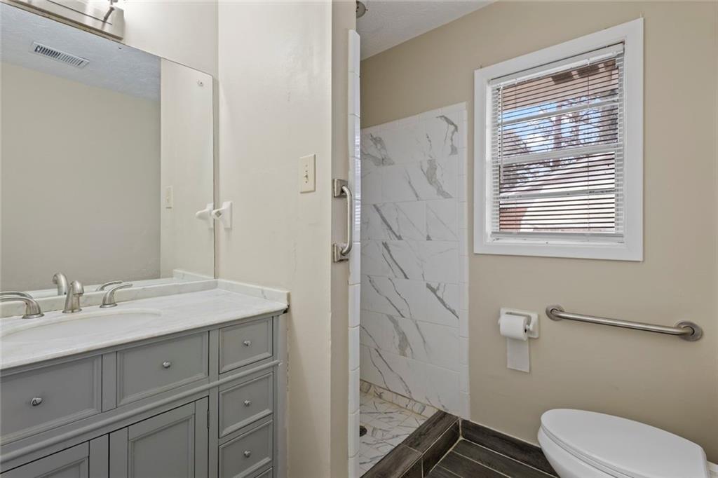 1201 Shoreham Drive Atlanta, GA 30349 - Photo 16 of 21 a bathroom with a granite countertop sink toilet a mirror a vanity and shower