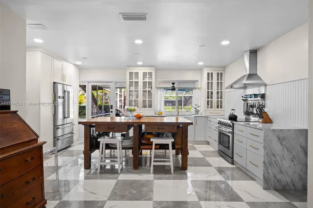 a kitchen with stainless steel appliances granite countertop a table chairs sink and stove top oven