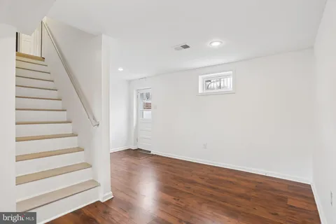 a view of an empty room with wooden floor fireplace and a window