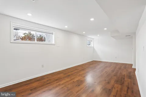 a view of an empty room with wooden floor and a fireplace