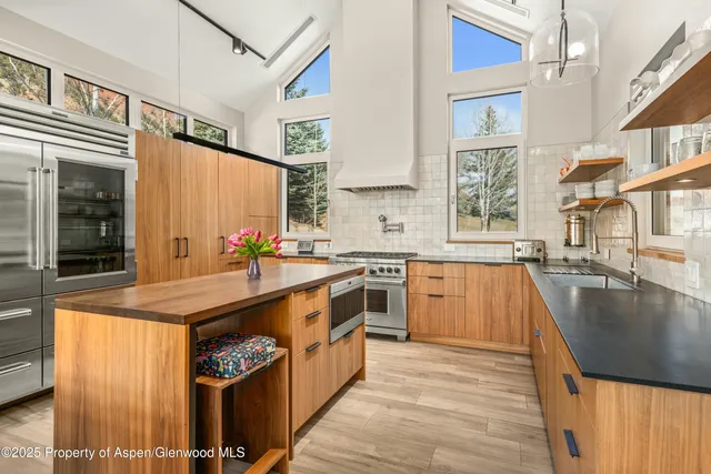 a kitchen with stainless steel appliances granite countertop a sink a stove and a refrigerator